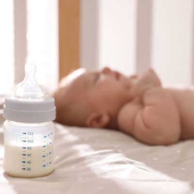 Newborn baby sleeping in background, focus on bottle of milk