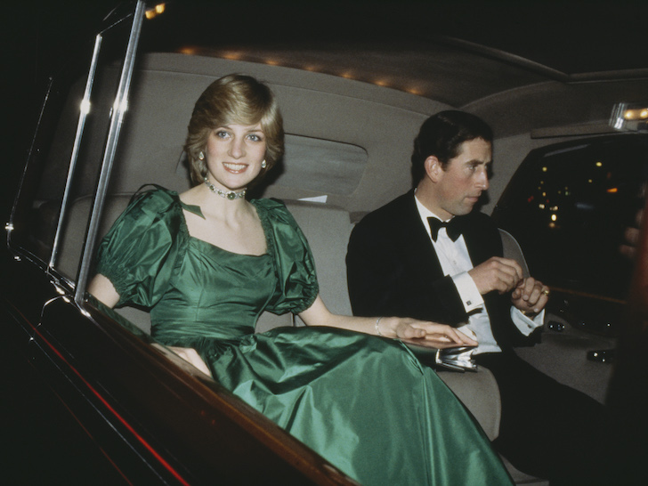 Princess Diana in a green dress smiling looking at the camera in the car with Prince Charles in a tuxedo sitting next to her looking uninterested