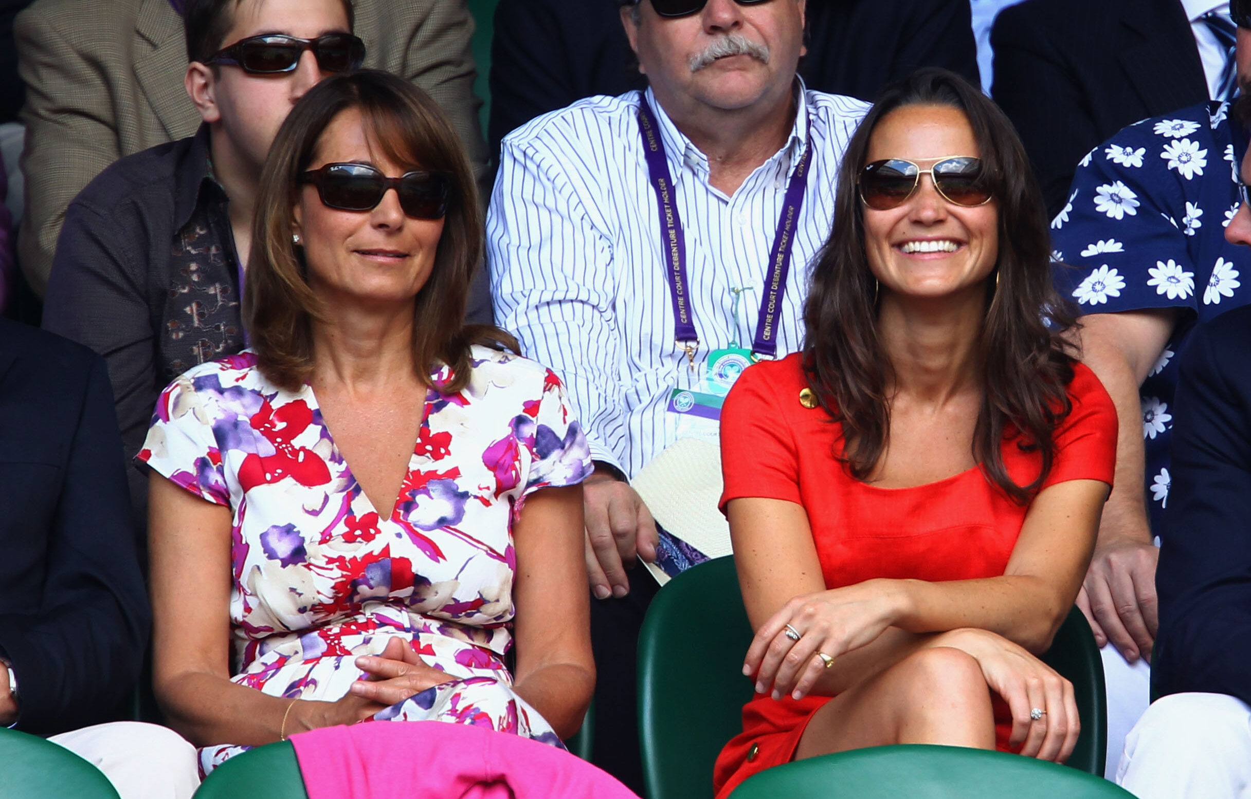 Carole Middleton (L) and Pippa smiling and sitting in sports bleachers wearing sunglasses