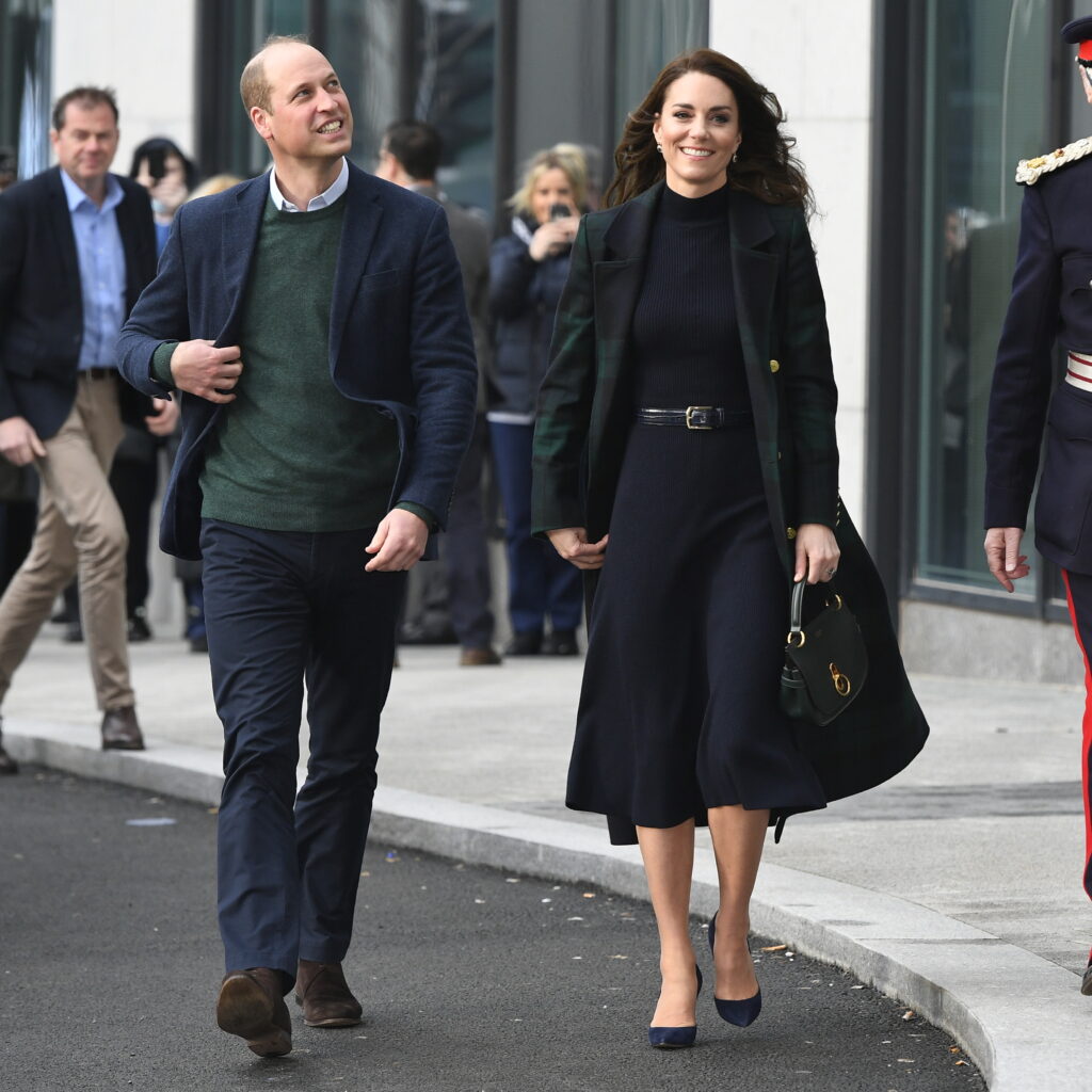 Prince William (L) in green sweater and navy blue pants walking outside together