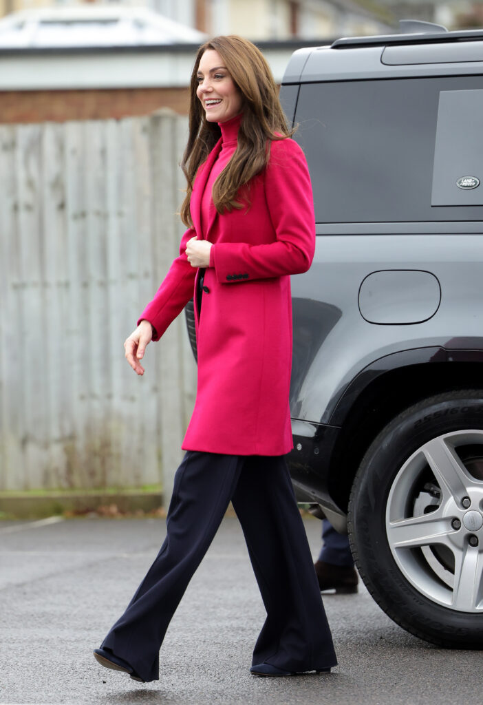 Kate Middleton walking outside in hot pink jacket and dark blue pants