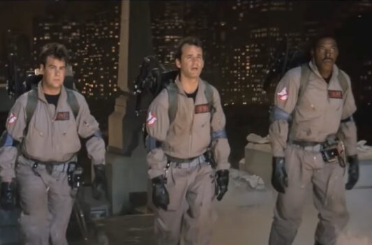 screenshot of the Ghostbusters walking up the courtyard of the Empire State Building in uniform