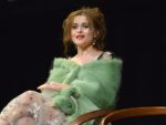 Helena Bonham Carter sits and speaks while wearing a green shawl and nude-colored skirt