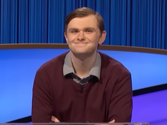 'Jeopardy!' contestant Jake DeArruda smiles on stage against blue backdrop