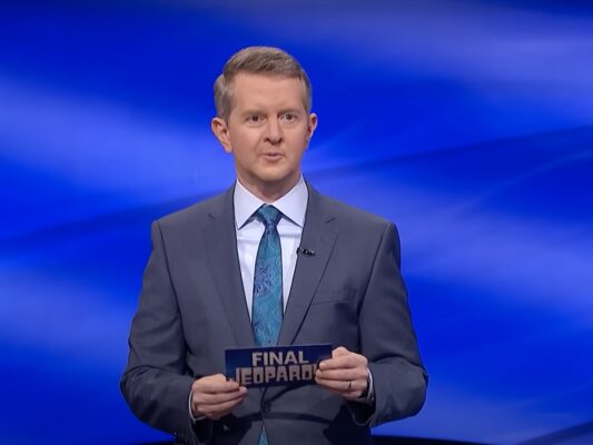 screenshot of ken Jennings hosting final Jeopardy in a grey suit and blue tie