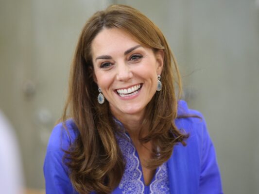 Kate Middleton smiles in bright blue top and matching cardigan