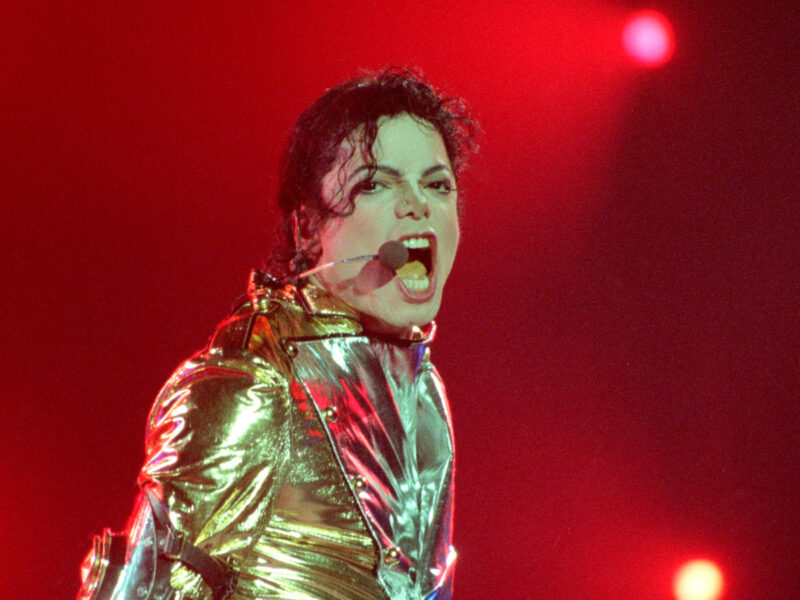 1996 photo of Michael Jackson singing on stage in a gold jacket