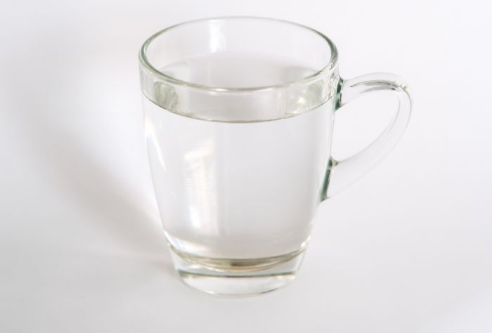 A clear mug of water on a white background