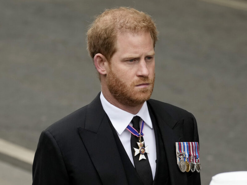 Prince Harry looking stern in a black suit and tie