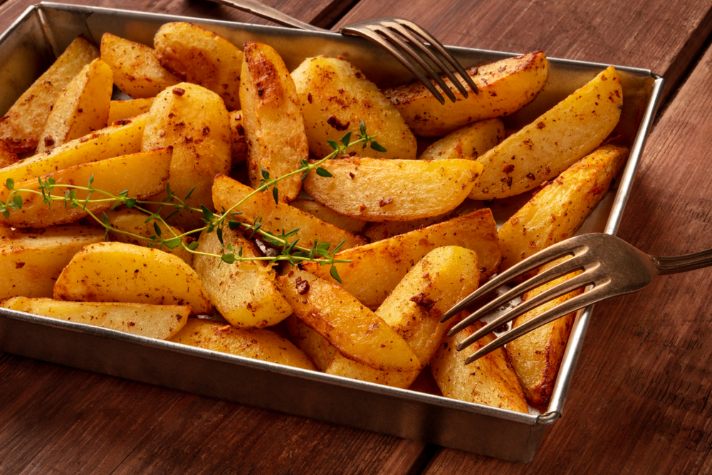 Potato wedges with thyme on a baking tray