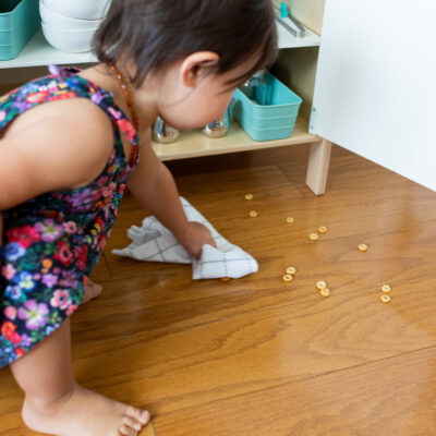 Toddler picking up cheerios off the floor.