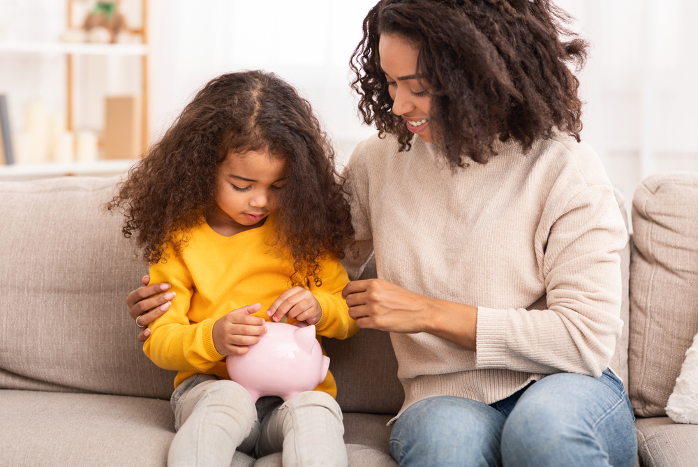 A mother with her daughter, who is holding a piggy bank.