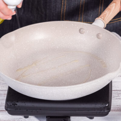 Woman spraying cooking spray onto nonstick frying pan
