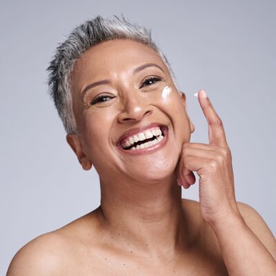 A smiling woman applying face cream