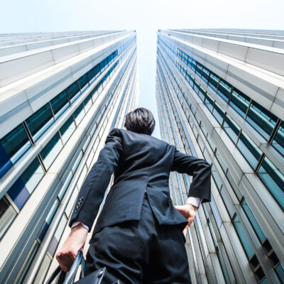 Businessman looking up at tall office buildings.