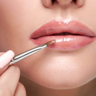 A woman applying a glossy lip product