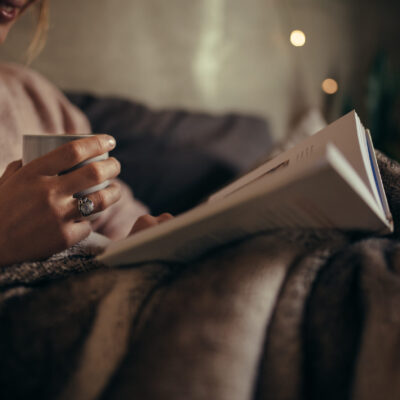 A woman in bed at night enjoying a good book.