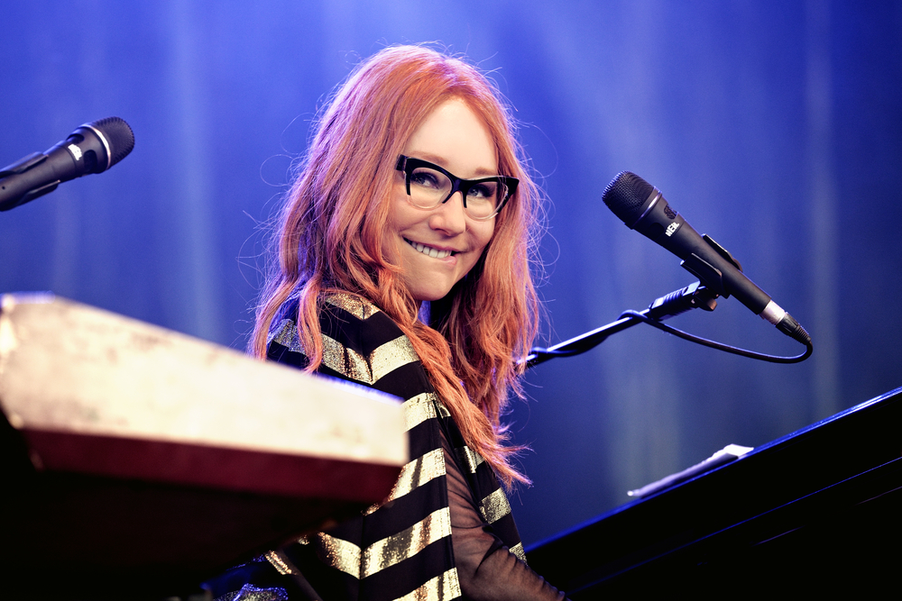 Tori Amos performs at her piano, smiling at the crowd
