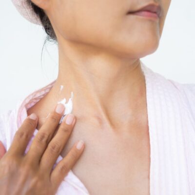 Middle-aged woman applying neck cream