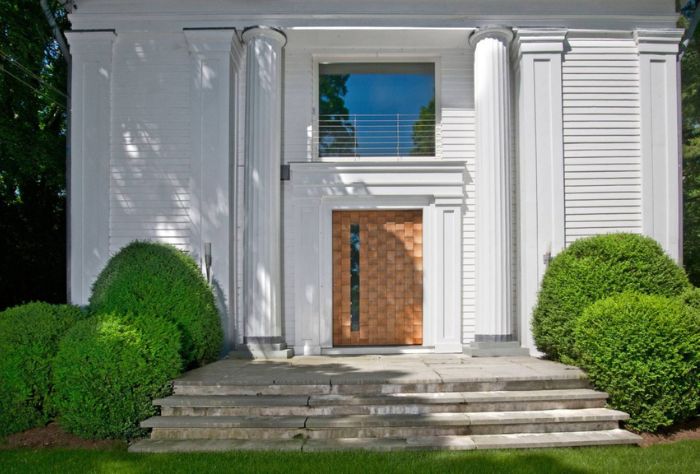 The front of the the home features large white columns, a large picture window, and a decorative wooden door