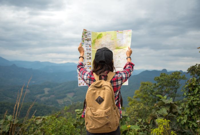 Woman looks at map in front of mountain range