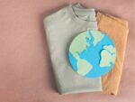 Folded clothing with paper earth on top of them, illustration of sustainable fashion