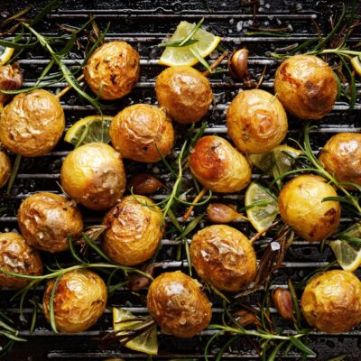 Roasted potatoes and various herbs and seasonings lying on a black background